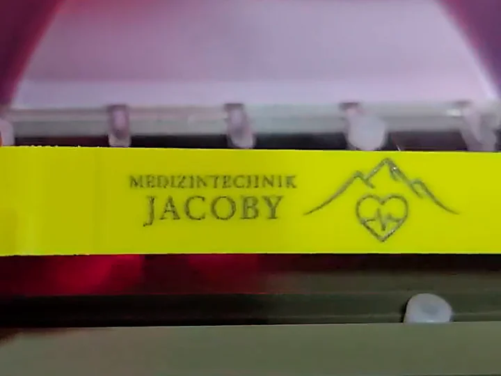 Mit dem Faserlaser gravierter gelber Spritzenhalter mit Schriftzug und Logo von Medizintechnik JACOBY