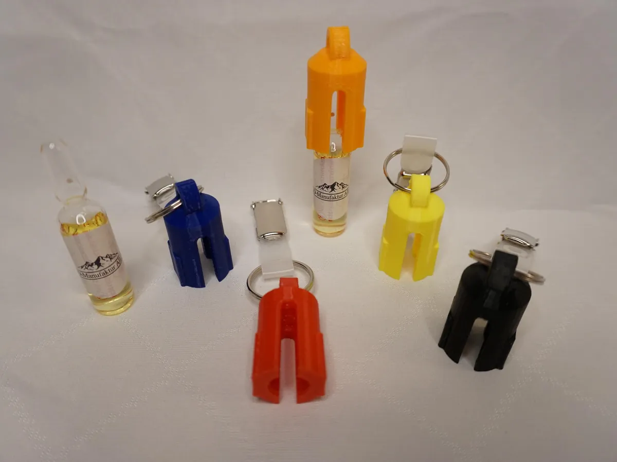Ampullenbrecher in Orange, Blau, Rot, Gelb und Schwarz mit Clips, links eine Glasampulle