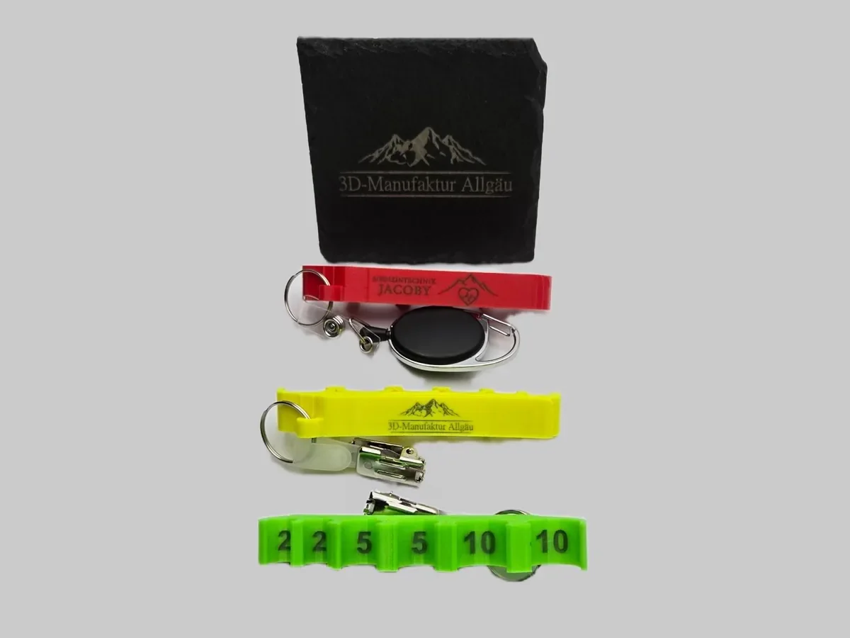 Lasergravierte Halter in Rot, Gelb und Neon Grün vor einer gravierten Schieferplatte