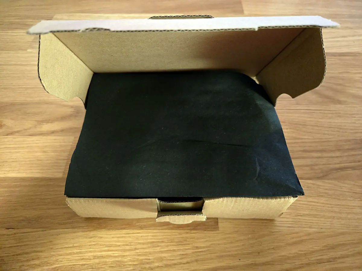 Geöffnete Versandschachtel mit schwarzem Seidenpapier