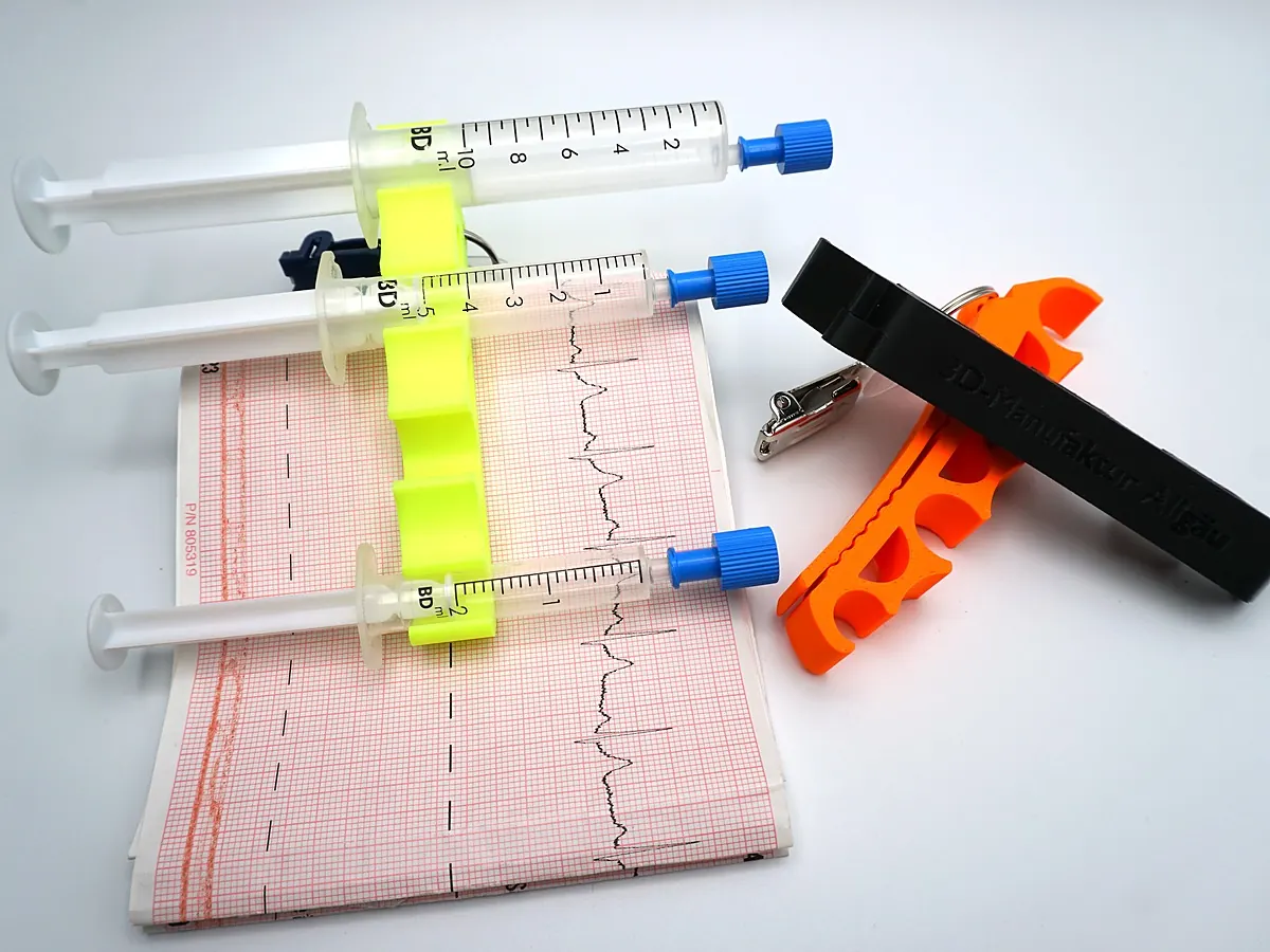 Gelber Spritzenhalter mit drei Spritzen auf einem EKG Streifen