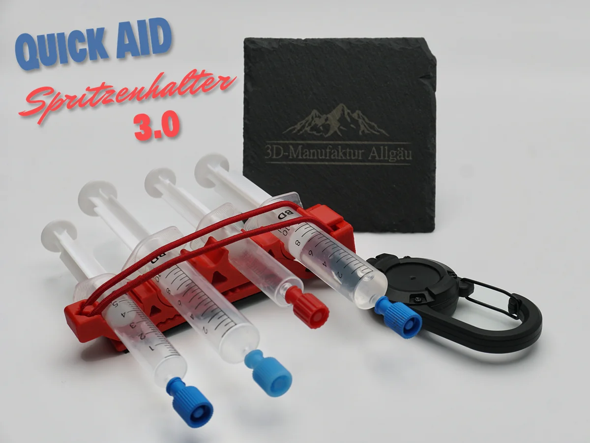 QuickAid Spritzenhalter 3.0 in Neon Rot mit zwei 10 ml und zwei 5 ml Spritzen, Gummikordel über den Spritzen und Clip, dahinter eine Schieferplatte mit dem Logo der 3D-Manufaktur Allgäu