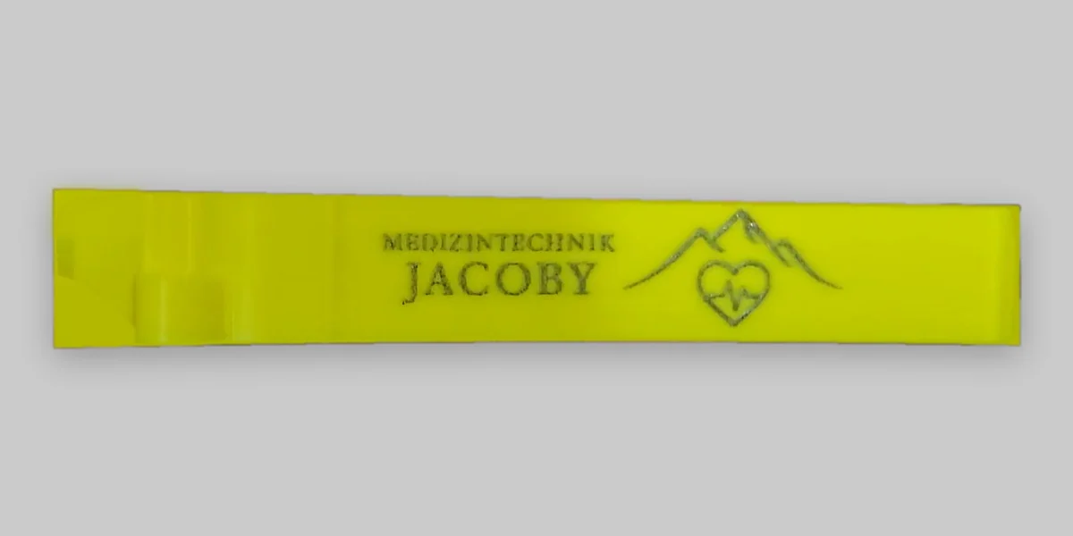 Gelber Spritzenhalter mit Lasergravur „Medizintechnik JACOBY“ und Logo